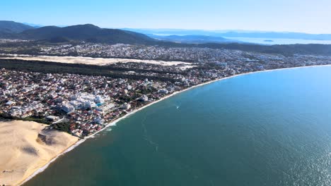 escena aérea de drones playa florianópolis vista desde la parte superior ciudad costera cerca del mar con montañas dunas horizonte edificios subdivisión urbana en la costa playa ingles y playa santinho en sunst