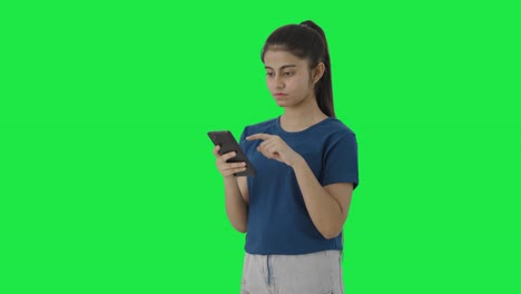 Serious-Indian-teenage-girl-scrolling-phone-Green-screen