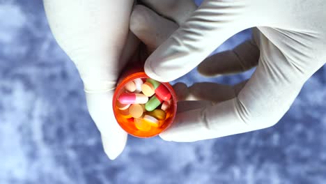 médico sosteniendo un recipiente de pastillas en guantes médicos