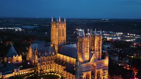 aerial drone video captures the renowned lincoln cathedral in lincolnshire, uk, at dusk, showcasing its majestic gothic architecture with illumination