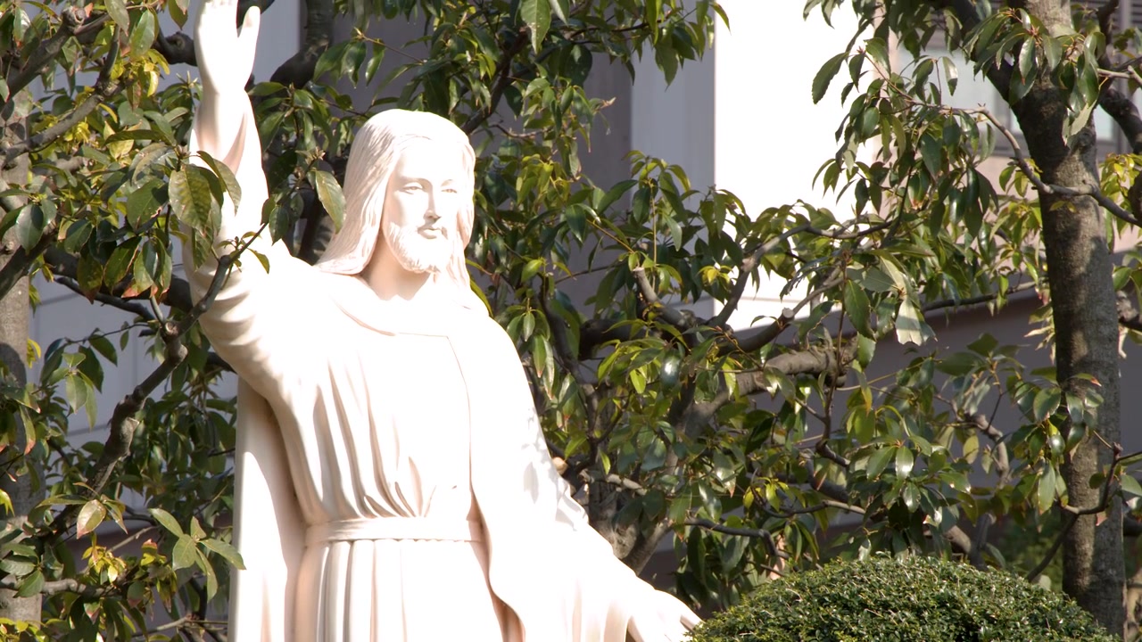 Langsom zoom ud afslører en hvid Jesus-skulptur, der står i en frodig japansk have.