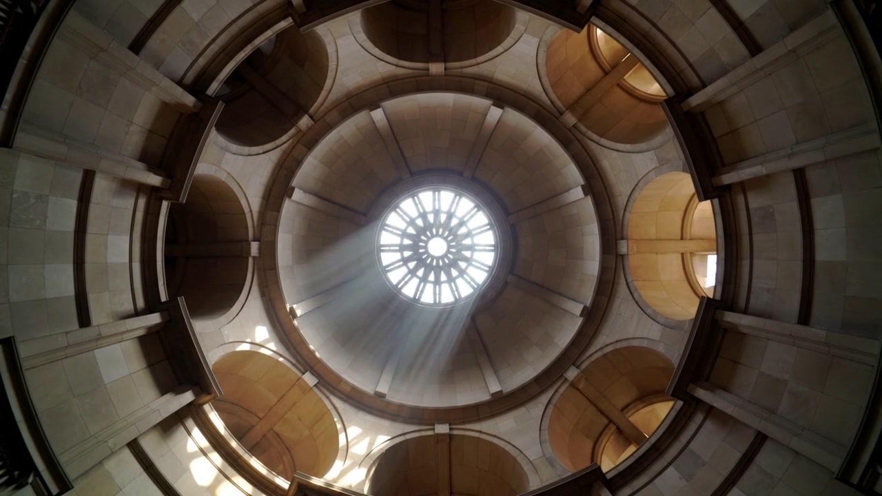 Luce solare che filtra attraverso un oculo, rivelando un soffitto a cupola all'interno di una rotonda e proiettando raggi pieni di polvere.