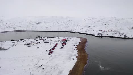 snowy arctic village with red cabins by the river