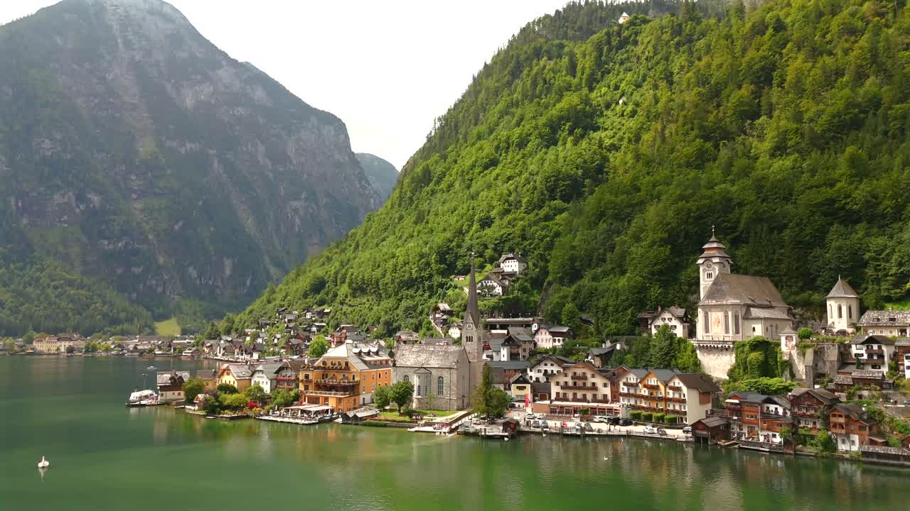 Aerial view of Hallstatt, Austria, captured by drone, showcasing its picturesque lakeside homes, majestic mountains, and the unique charm of this enchanting alpine village.
