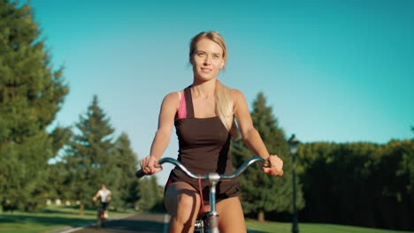 Mujer-Fitness-Ciclismo-En-Bicicleta-En-El-Parque-De-La-Ciudad-En-El-Día-De-Verano.-Mujer-Joven,-Bicicleta
