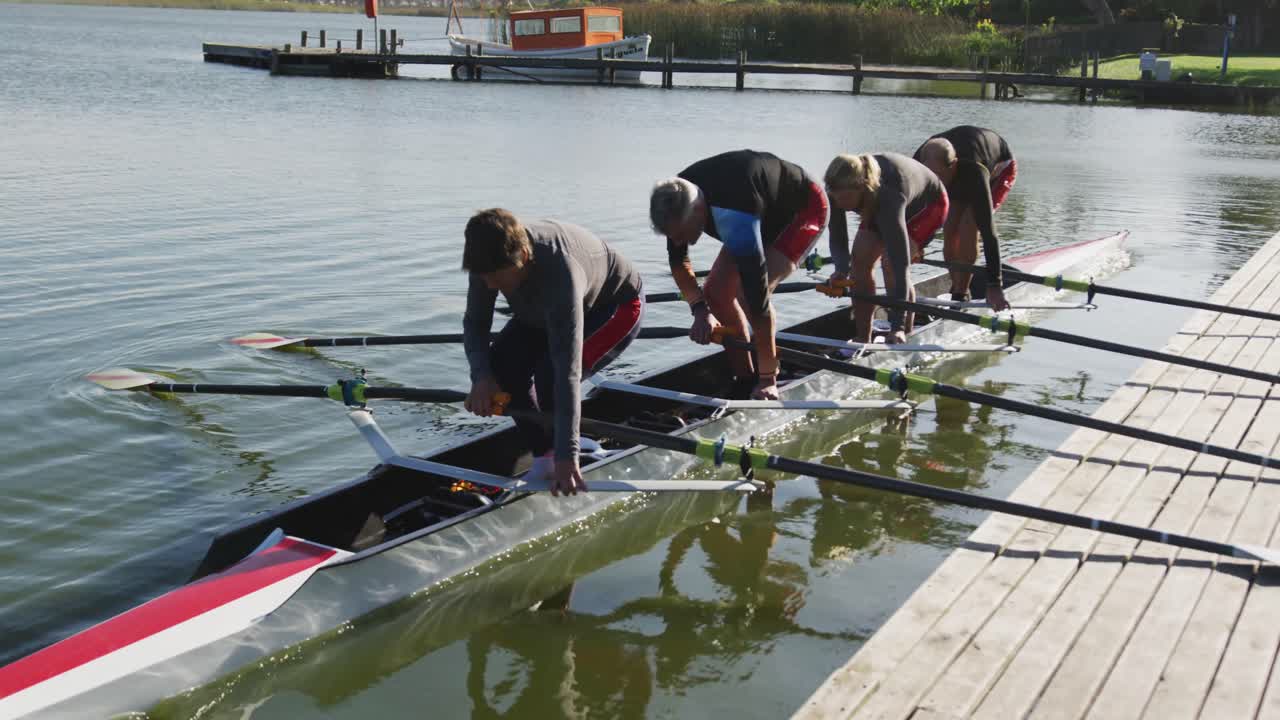 Four senior caucasian men and women preparing rowing boat in a river