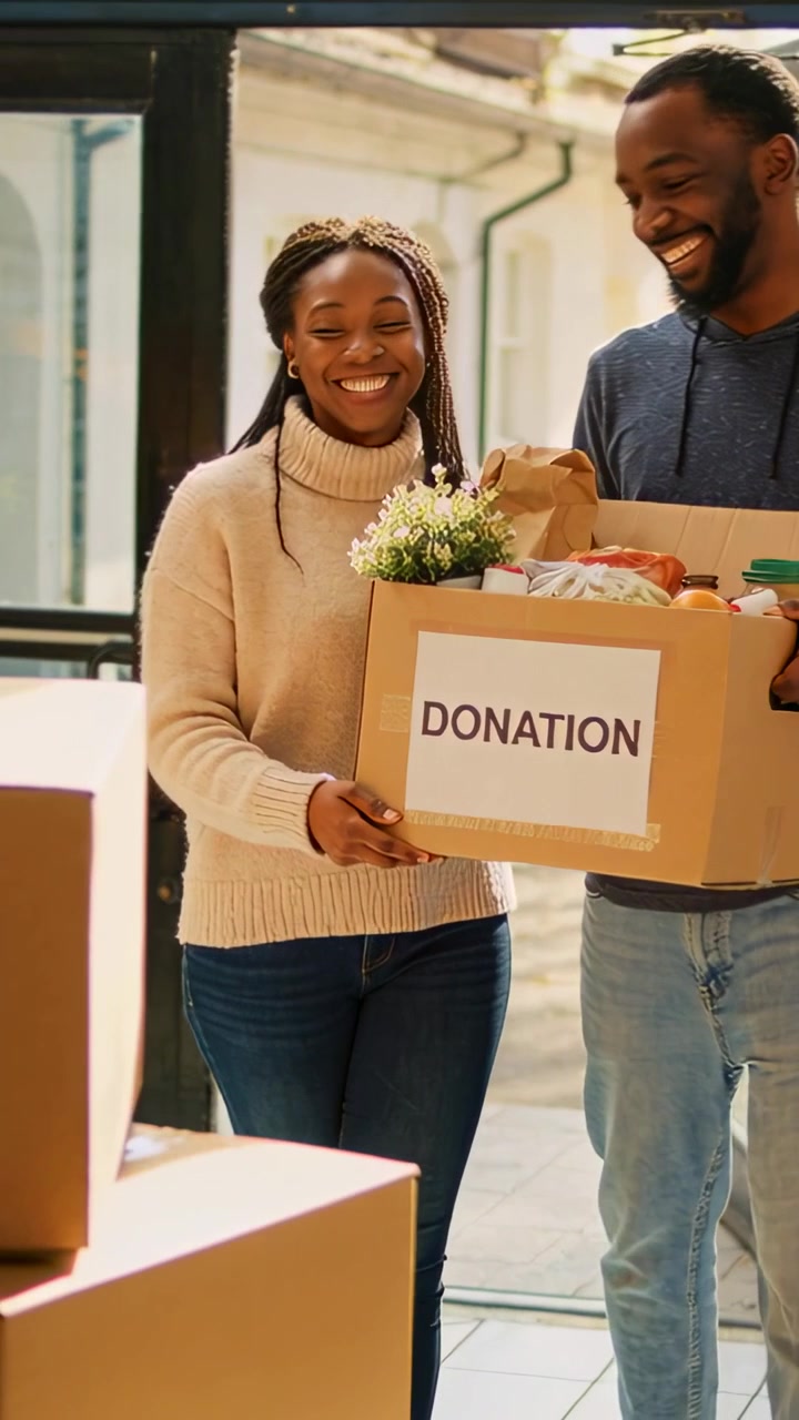 Vertical video: Entering donors holding DONATION box at glass door, man hoodie with plant to donate