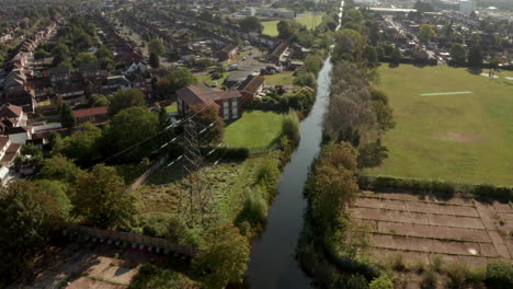 Descending-aerial-shot-of-Electricity-pylon-running-along-a-canal