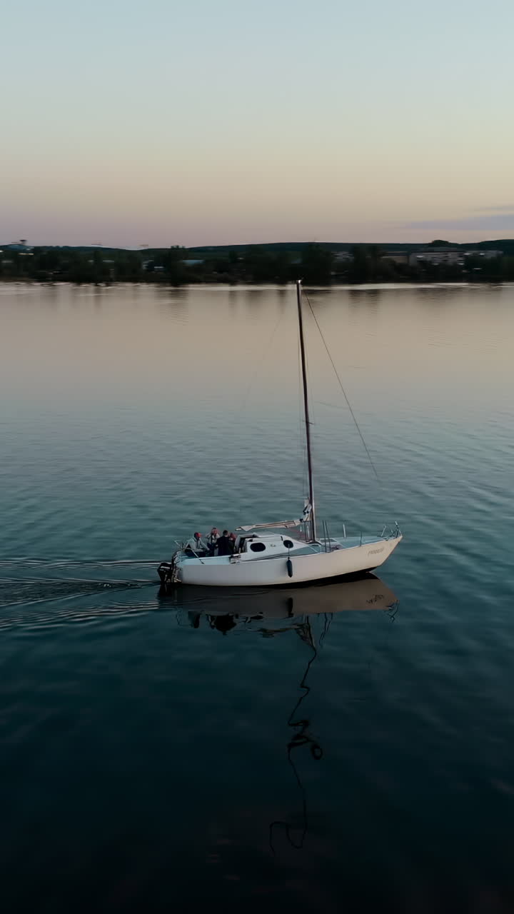 Veduta Aerea di uno Yacht che Naviga su Acque Blu Tranquille con lo Skyline di una Città Moderna sullo Sfondo