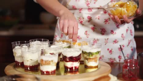 woman preparing layered fruit desserts