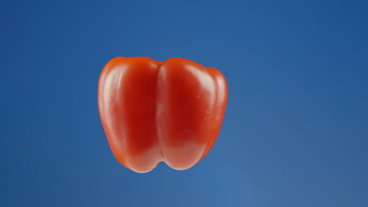 파란 스튜디오 배경 에 대하여 공중 에서 회전 하는  ⁇ 은 고추 가 떠다니고 있다