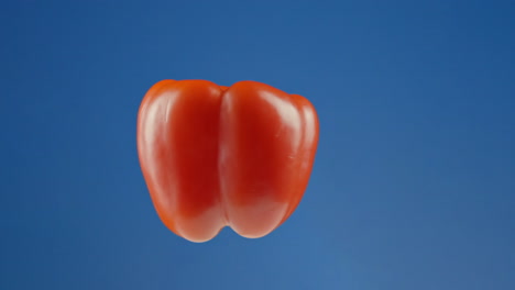 Levitating-Red-Bell-Pepper-Spinning-in-Mid-Air-Against-a-Blue-Studio-Background