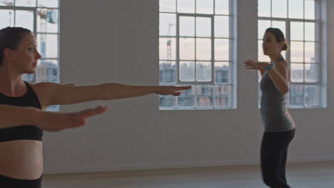 yoga class instructor teaching healthy pregnant women practicing warrior pose enjoying group training exercise in fitness studio at sunrise