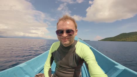 a cheerful man wearing sunglasses and a wetsuit enjoys a boat ride on a calm, expansive sea