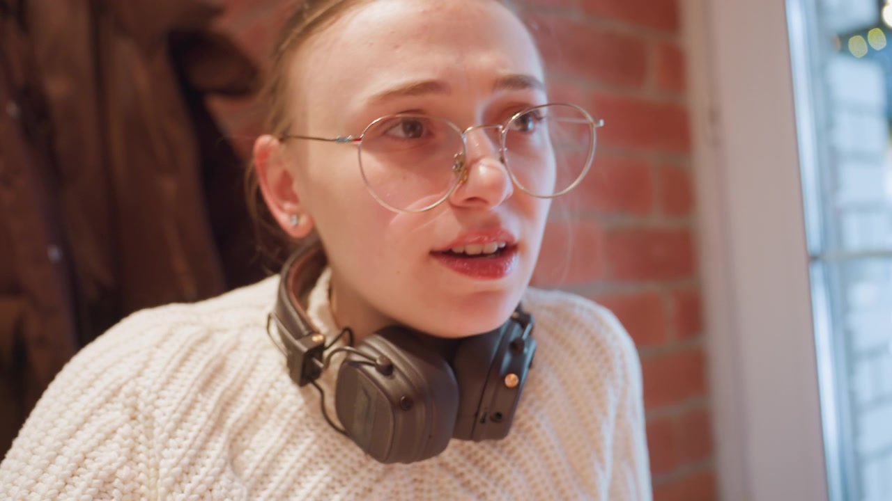 Thoughtful Young Woman Wearing Glasses and Headphones