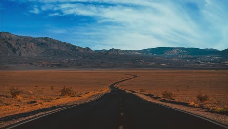 death valley national park cinemagraph / seamless video loop time lapse of a lonely straight highway road and clouds moving along the blue sky above the dry, hot, empty and remote desert of nevada and california, united states of america.