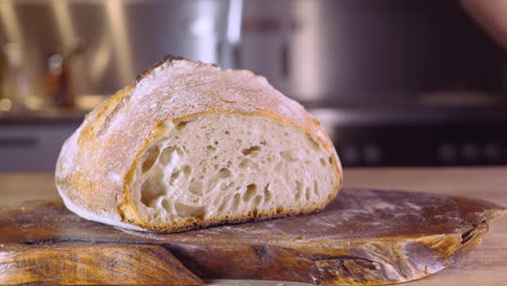 Die-Hände-Des-Mannes-Bewegen-Das-Sauerteigbrot-Auf-Einem-Holzbrett