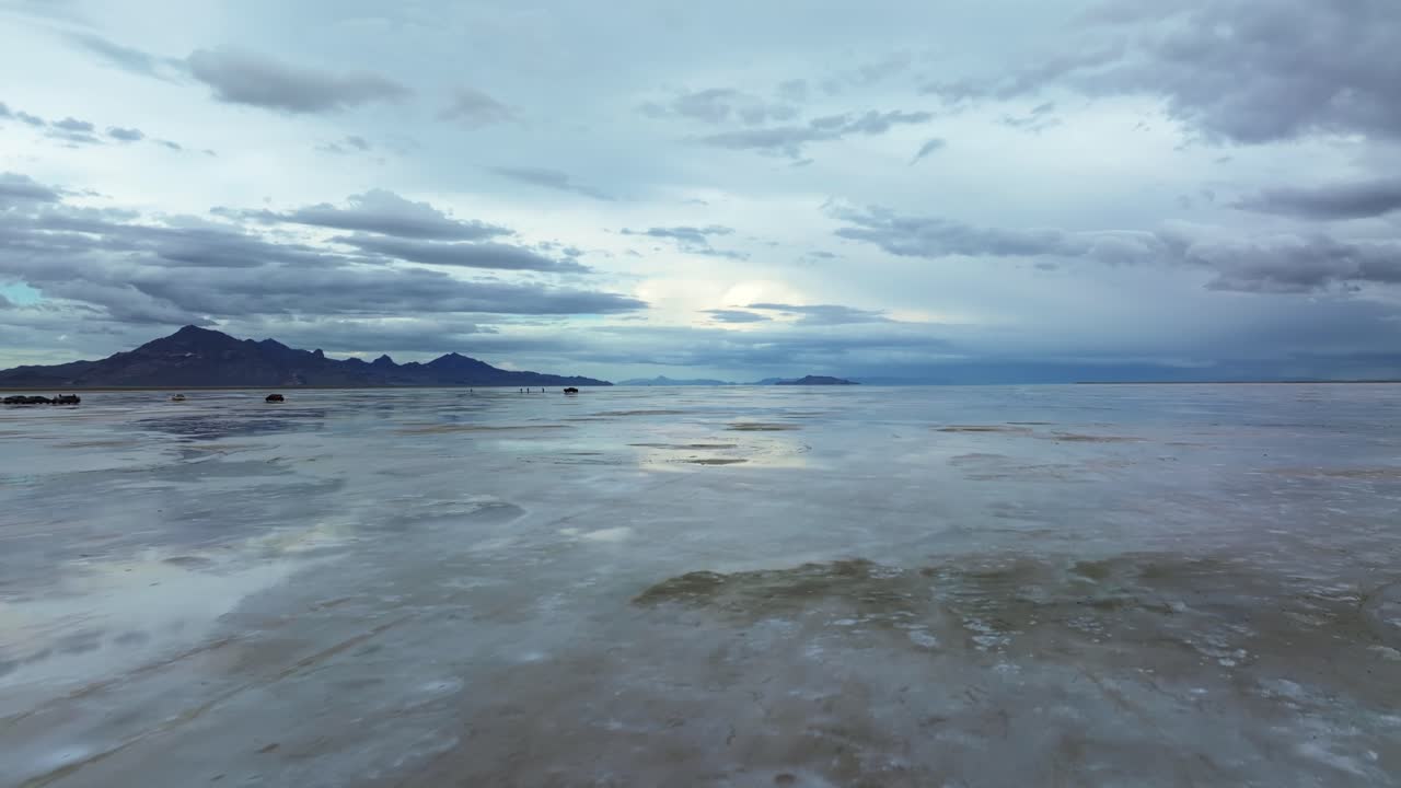 Wide Aerial drone dolly in rising shot of the famous Bonneville Salt Flats in Utah near Wendover, Nevada flooded from rain, creating mirage reflections with mountains on a stormy spring evening
