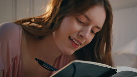 chica de primer plano escribiendo un cuaderno a la luz del sol. feliz inspirada mujer comparte pensamientos