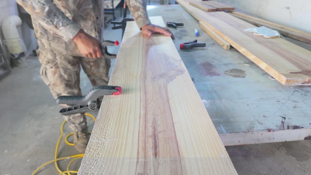 Man working with wood planks using clamps in workshop. Carpentry Manual labor