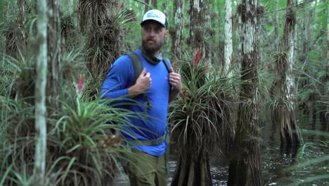 un hombre pasa junto a plantas de bromelias mientras recorre a pie los everglades de florida