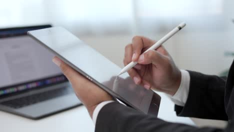 businessman using stylus pen signing contract on digital tablet at work in office indoors. close up hand write business agreement of contract. electronic signature on tablet computer.