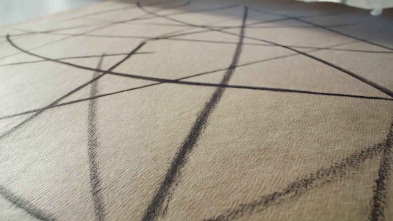 Punto di vista basso su una superficie fibrosa beige contrassegnata da tratti di carboncino scuro che si intersecano, incroci diagonali, geometria curva, leggere variazioni d'ombra e un leggero cambiamento di messa a fuoco che formano un astratto minimale.