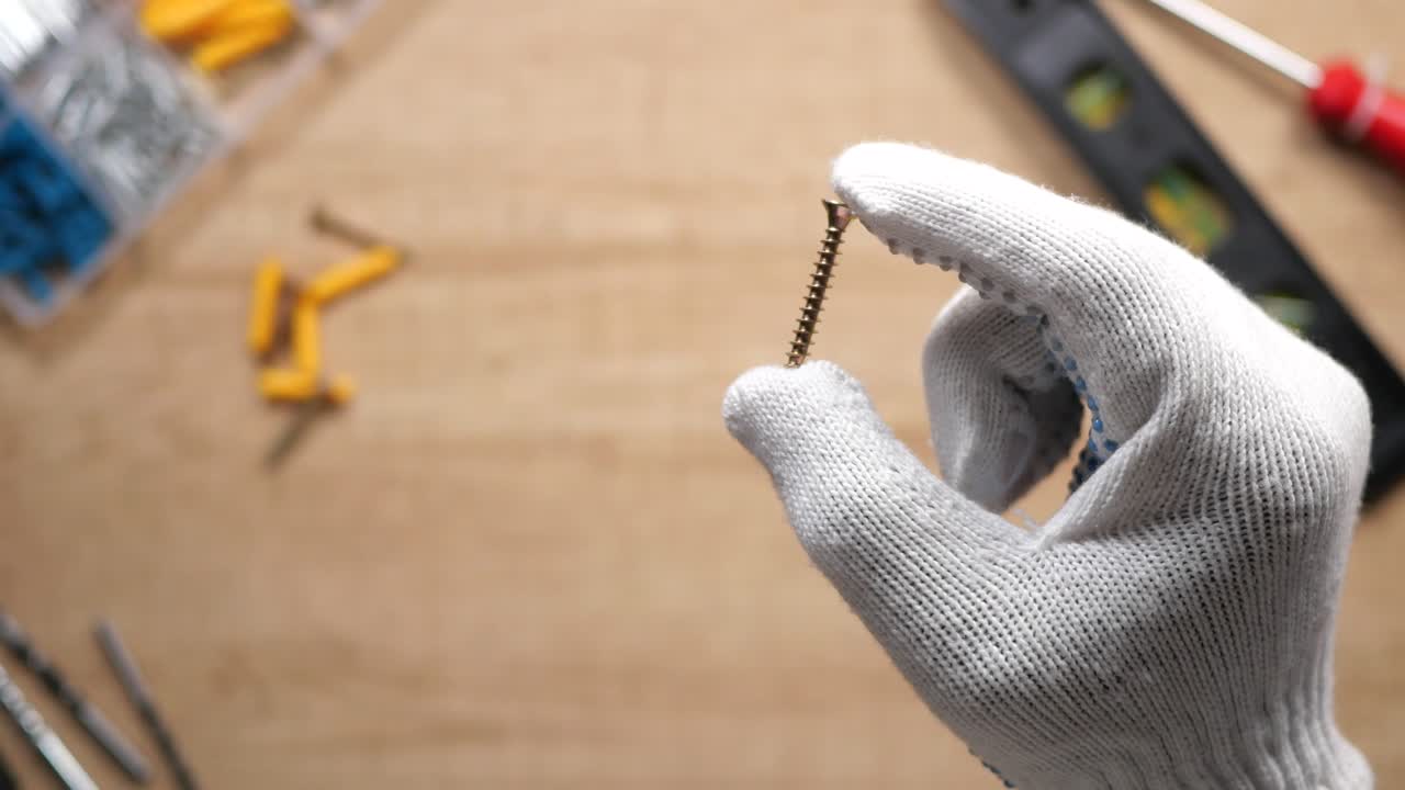 Hand in glove holding a screw