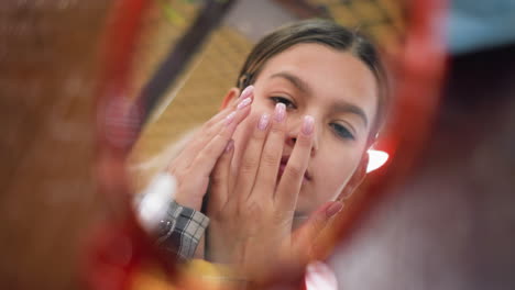 el reflejo en el espejo de una chica masajeando el rostro con manos suaves, mejorando la rutina de cuidado de la piel, la iluminación suave destaca el cuidado de sí mismo, la belleza y el bienestar para un rostro brillante e hidratado
