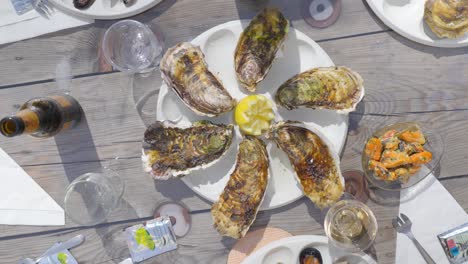 the table is adorned with an exquisite display of oysters, their shells glistening with seawater, arranged meticulously alongside a selection of fine wines