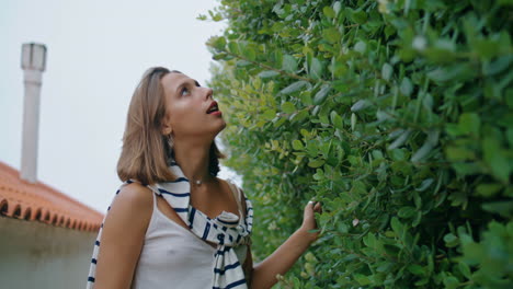 romantic girl touching leaves bushes. beautiful woman enjoying nature on trip.