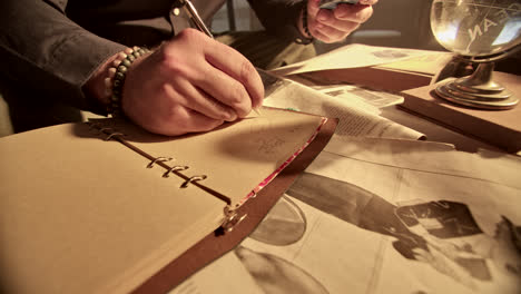 person writing in vintage notebook at desk