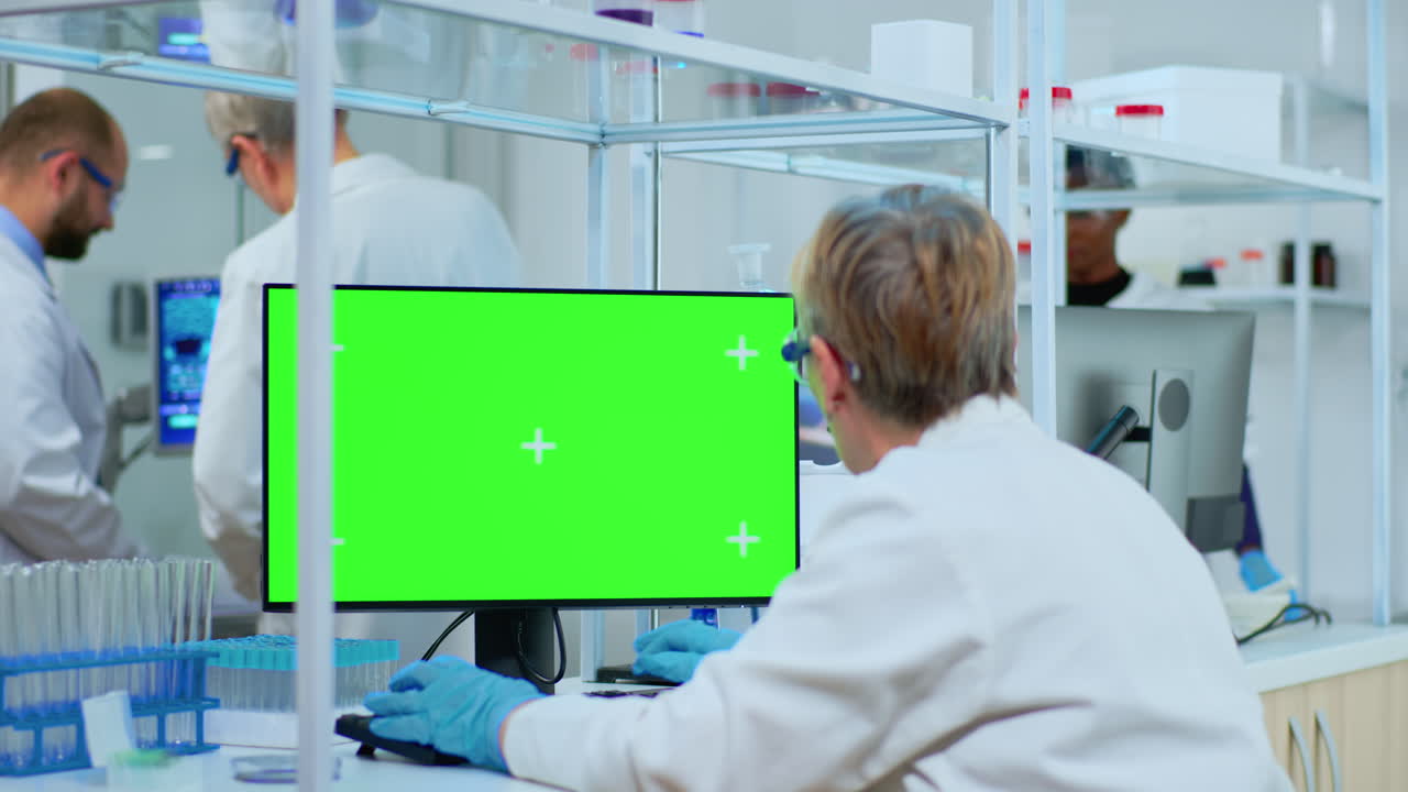 Elderly researcher looking at chroma key display in lab