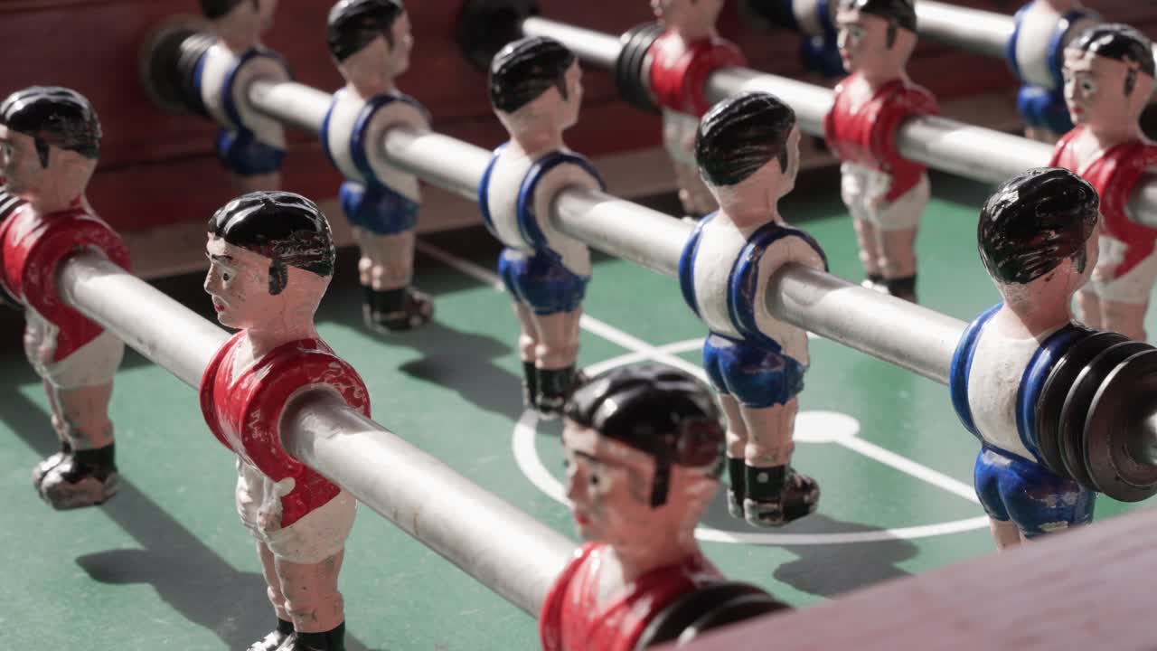 red and blue foosball players face off on classic game table under sunlight