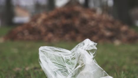 cambio de inclinación de la bolsa de plástico de basura en el suelo y las hojas se apilan y luego la casa de madera en el fondo en estilo báltico