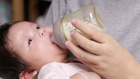 madre alimentando a su bebé recién nacido con un poco de leche mientras acuna a su hijo en sus brazos mientras duerme profundamente