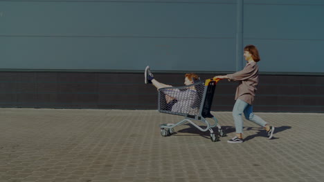 two girls having fun with a shopping cart