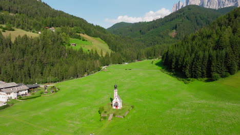 Alpine meadow with hikers near Church of St. John in summer Dolomites setting
