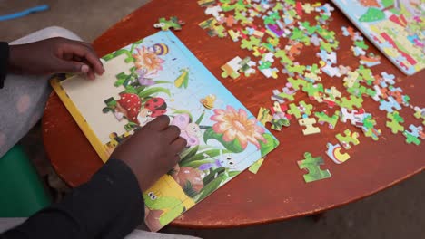 african poor kid playing doing a cartoon children's puzzle at the orphanage