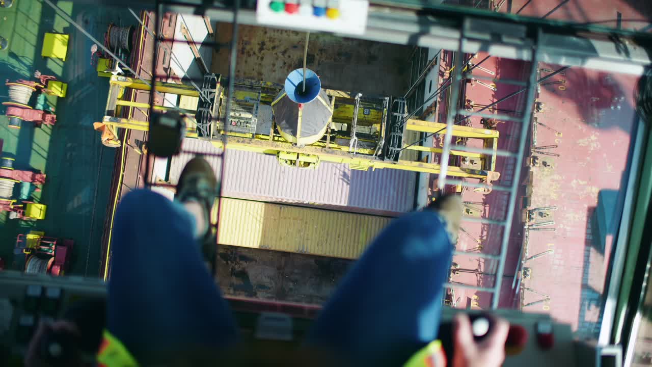 Looking down between industrial harbour crane operator legs loading ...
