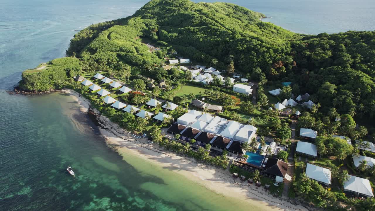 High aerial pullback showing reef, ocean, and lush hills around secluded Tokoriki resort, Fiji