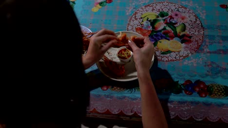 a woman is eating shrimp with her hands in a cafe on the street