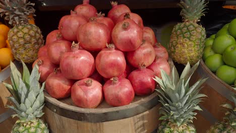 un puesto de frutas con granadas, piñas y manzanas verdes