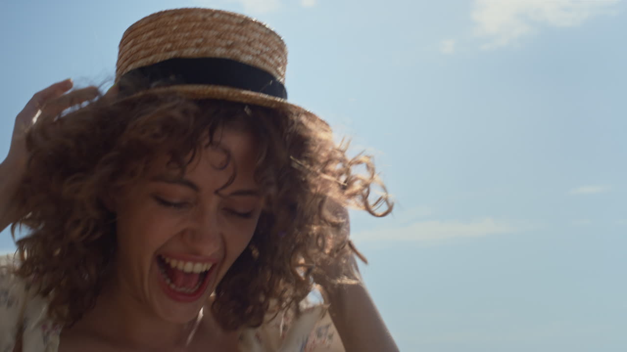 Excited woman jumping holding straw hat on head closeup. Lady having fun.