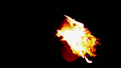 fire dancer bringing fire past his face in the darkness