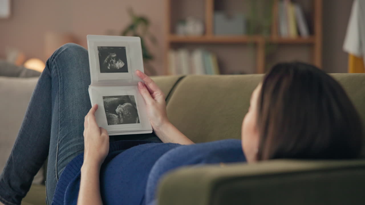 Woman looking at ultrasound photos on couch