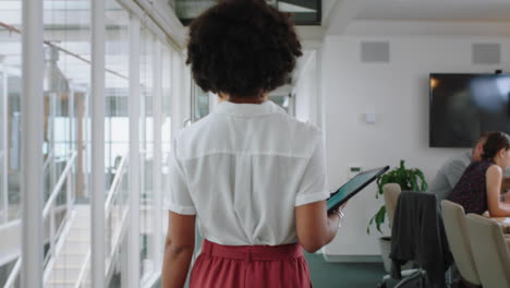 Vista-Trasera-De-Una-Mujer-De-Negocios-De-Raza-Mixta-Caminando-Por-La-Oficina-Sosteniendo-Una-Tableta-Con-Una-Carrera-Exitosa-En-El-Lugar-De-Trabajo-Corporativo-4k