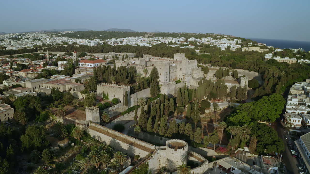 una vista aérea de la ciudad de la isla de rodas en grecia que contiene clips del casco antiguo medieval, el antiguo faro en el puerto, viejos molinos de viento, playas y una increíble puesta de sol