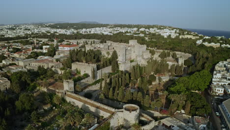 Eine-Luftaufnahme-Der-Stadt-Rhodos-In-Griechenland-Mit-Ausschnitten-Der-Mittelalterlichen-Altstadt,-Dem-Alten-Leuchtturm-Am-Hafen,-Alten-Windmühlen,-Stränden-Und-Einem-Atemberaubenden-Sonnenuntergang