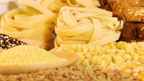 a variety of grains and pasta displayed in warm lighting, highlighting textures and colors in a close-up composition